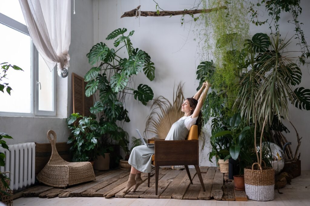woman stretching on a chair surrounded by plants. A huge window in front of her.